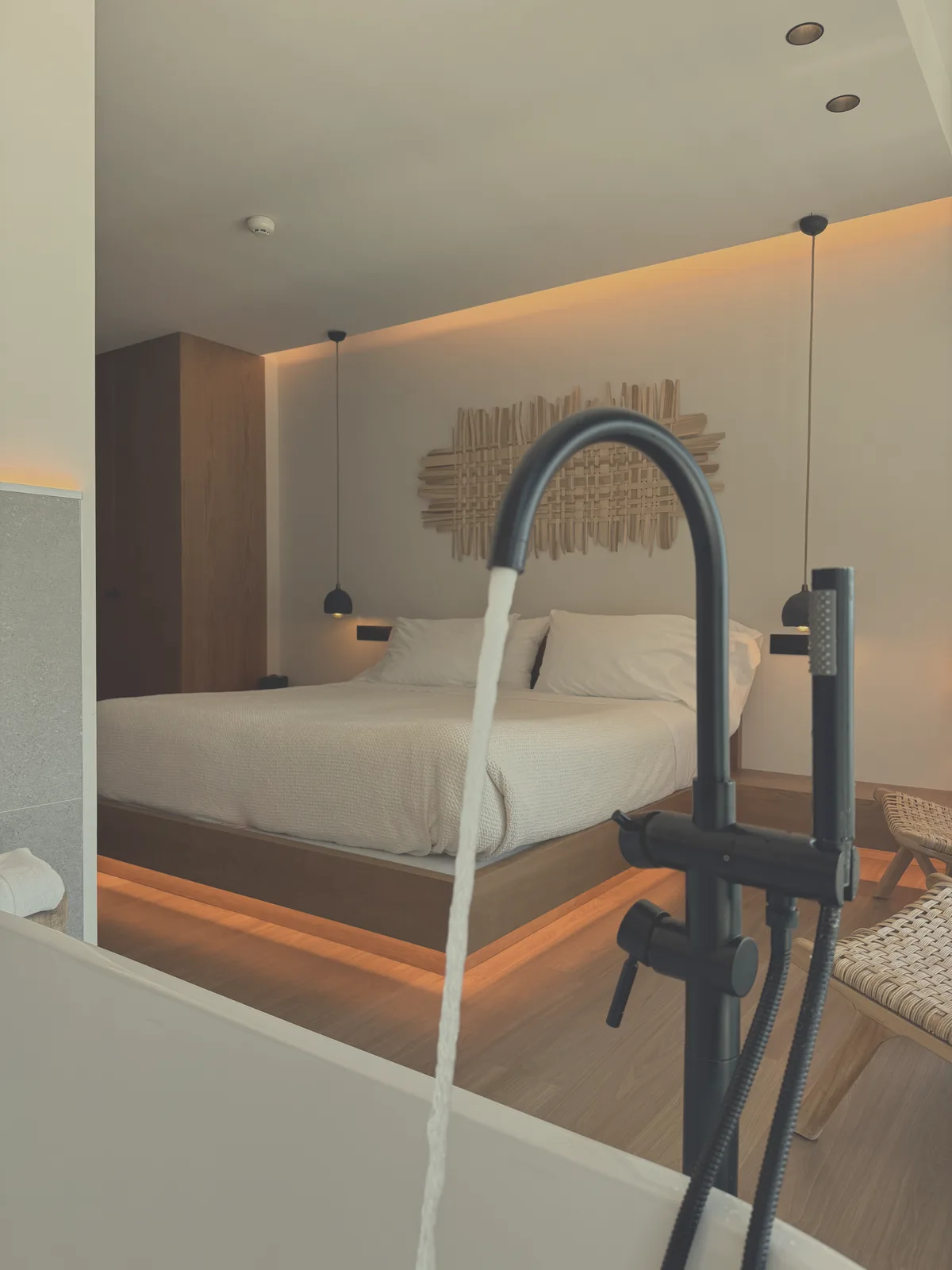 Bañera exenta llenándose frente a la cama en la habitación Slow Experience de Malates