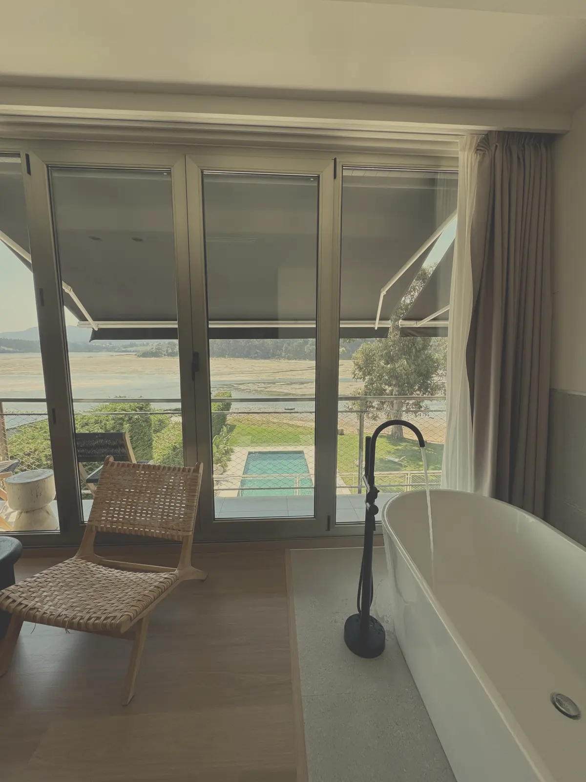 Bañera exenta junto al ventanal con vistas a la piscina y a la ría de Foz en Malates