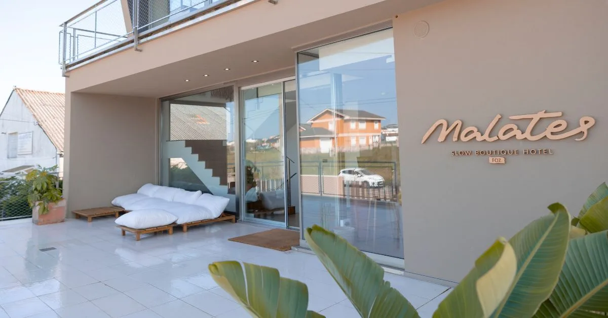 Entrada del hotel en Foz Malates con el rótulo y una cama balinesa de exterior