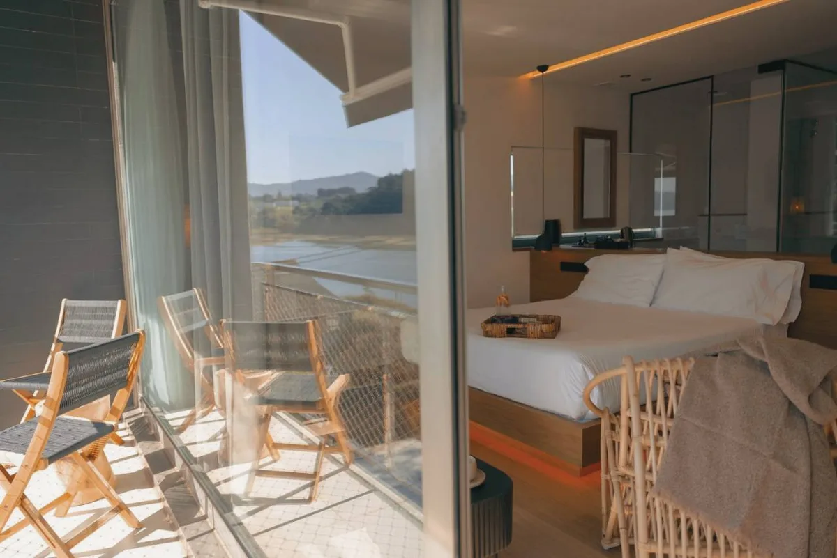 Habitación Signature del hotel en Foz Malates con ventanal, dos sillas y vistas a la ría
