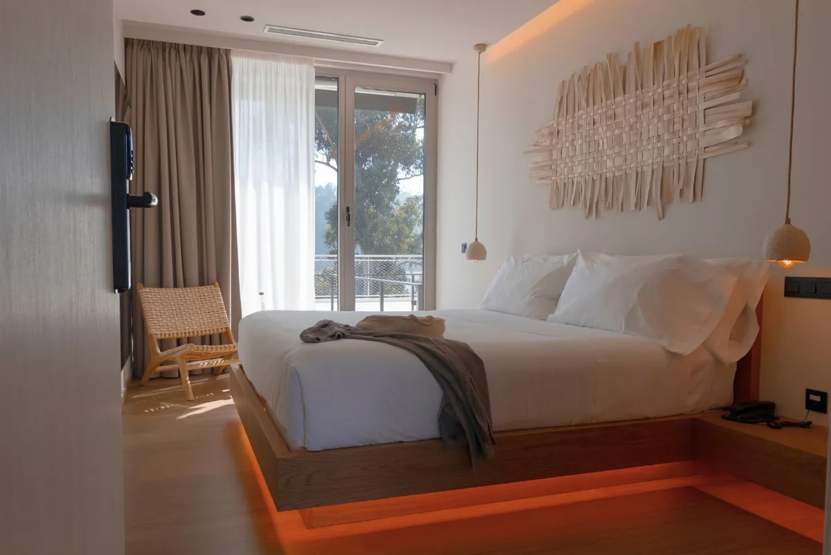 Habitación Infinity Albor del hotel en Foz Malates con cama blanca, manta gris y ventana al bosque